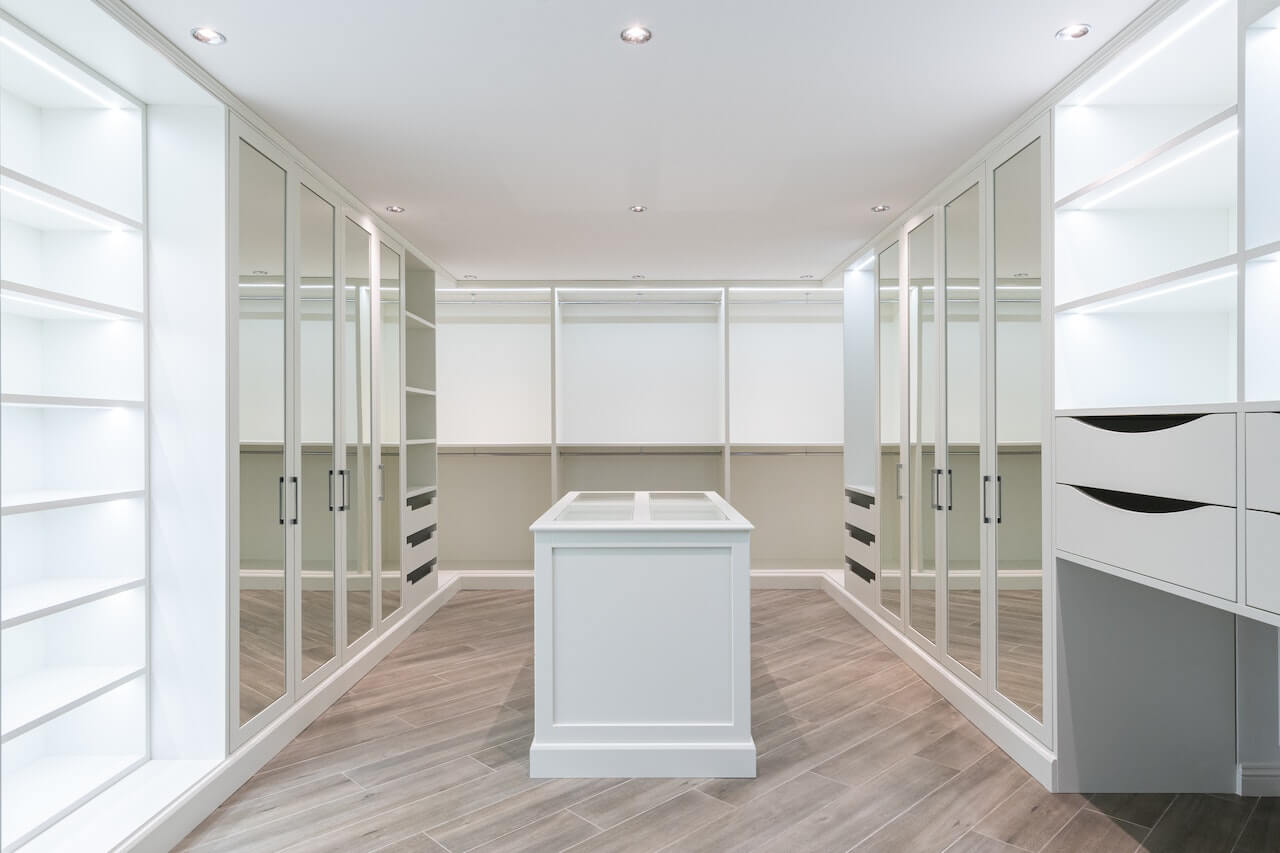 Spacious and Organized Walk-In Wardrobe Design with Shelving, Hanging Space, and Mirrors.